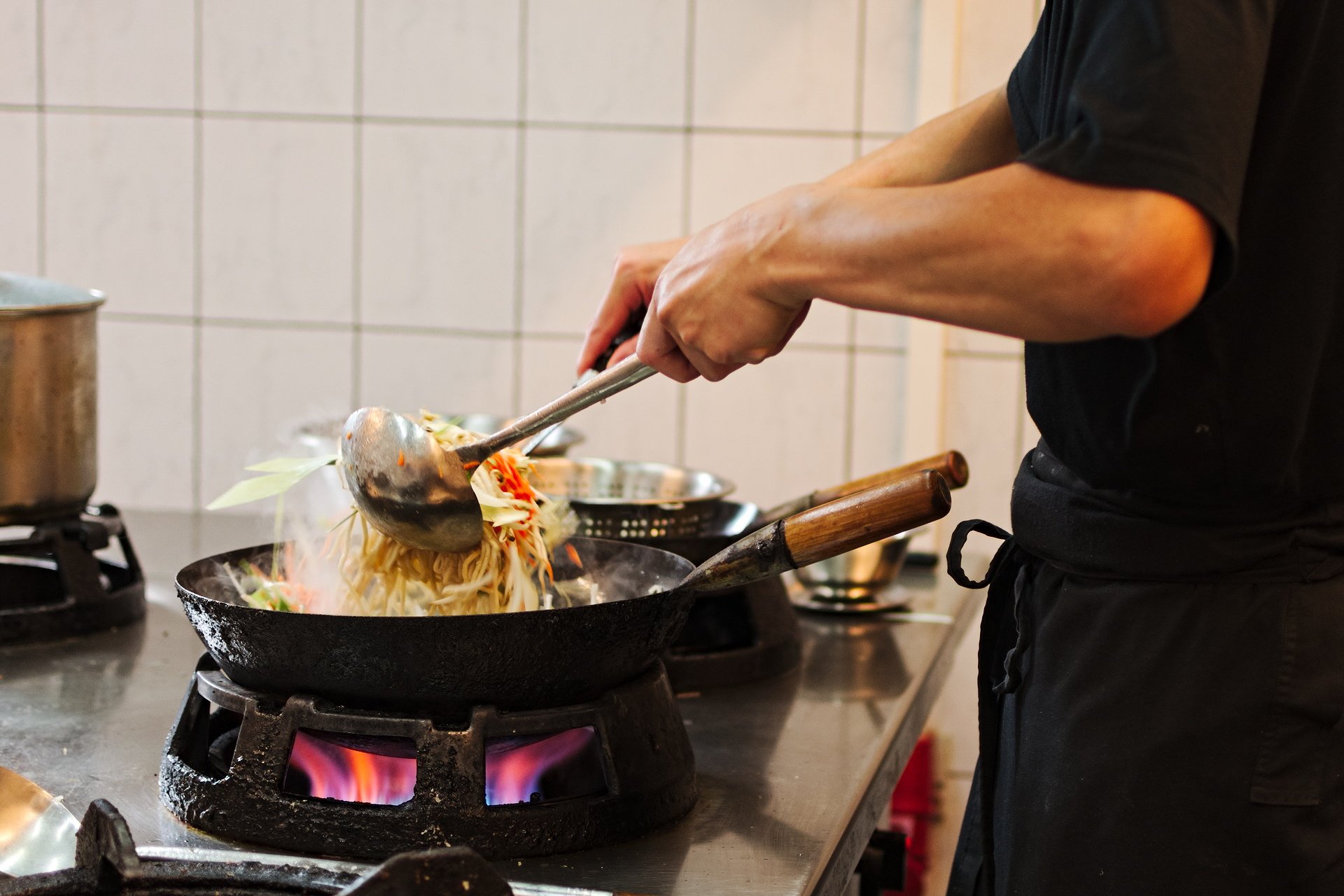 Kok tilbereder nudler i wok på Asian Taste